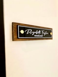 a wooden sign mounted to the side of a white wall