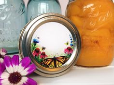 two jars filled with yellow and purple flowers next to each other on top of a shelf