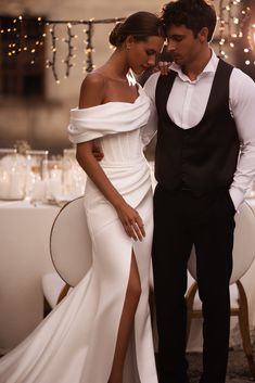 a man and woman standing next to each other in front of a table with candles