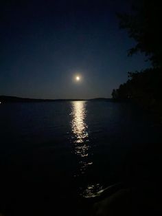 the moon is shining brightly over the water