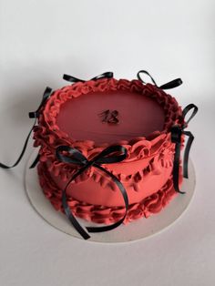 a red cake sitting on top of a white plate with black ribbon around the edges