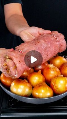 a person holding a large piece of meat in front of some onions on a stove