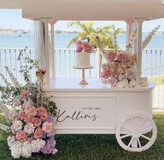 a wedding cake stand with flowers on the grass and water in the backgroud