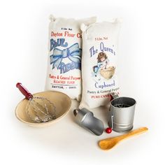 two bags of flour, measuring spoons and other kitchen items on a white surface