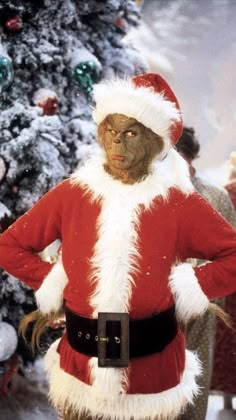 a man dressed as santa clause standing in front of a christmas tree