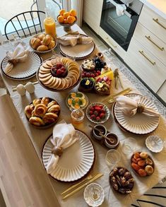 the table is set with breads, pastries and fruit