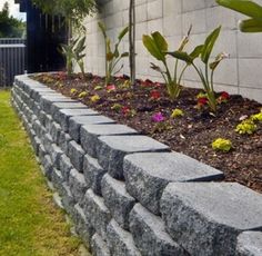 a stone wall with flowers growing in it