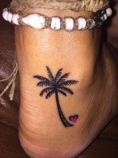 a small palm tree and heart tattoo on the side of someone's foot,