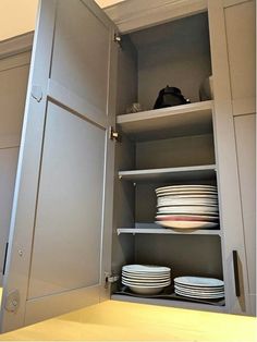 an open cabinet with plates and bowls in it