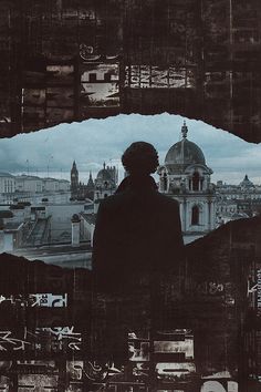 a man standing in front of a window looking out at a cityscape with buildings