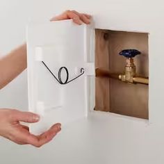 two hands holding an open box with a drawing on it and a water faucet in the background