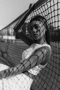 black and white photograph of a woman holding a tennis racket in front of a net