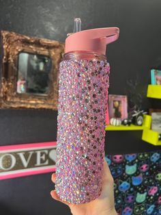 a person holding a pink and purple glittered water bottle