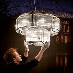 a man is holding up a chandelier in the dark