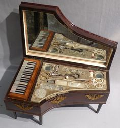 an antique musical box with keys and other items in it's display case on a white surface