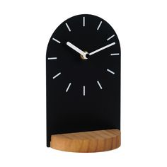 a black clock with white numbers on the face and wooden stand in front of it