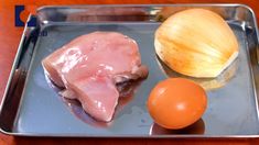 an onion and meat are on a metal tray next to each other, including an egg