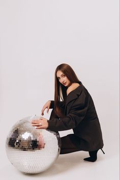 a woman kneeling down next to a disco ball