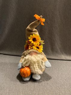 a stuffed animal with sunflowers on it's head and an orange pumpkin