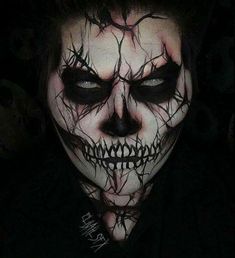 a man with dark makeup and black hair wearing a skull face paint make - up