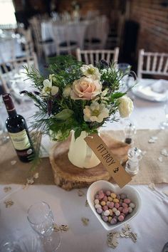 the table is set with wine, flowers and place cards for guests to sit at