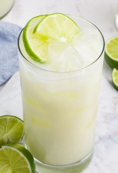 a close up of a drink with limes around it