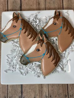 two decorated cookies shaped like horses on a plate