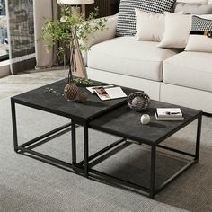 two tables sitting on top of a carpeted floor in front of a white couch