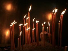 many lit candles in a metal bowl on a table with some lights coming from them