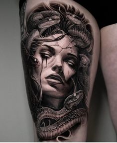 a woman's leg with a tattoo on it and a snake around her neck