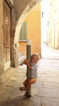 a small child is holding onto a pole