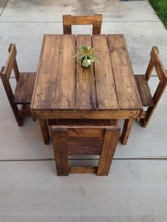 a wooden table and chairs with a potted plant sitting on top of one chair