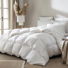 a large white comforter sitting on top of a bed next to a floor lamp