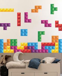 a person laying on top of a bed in front of a wall with colorful blocks