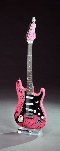 a pink and black guitar sitting on top of a table