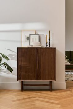 a wooden cabinet sitting in the corner of a room next to a potted plant