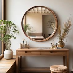 a wooden desk with a mirror above it next to a window and potted plant