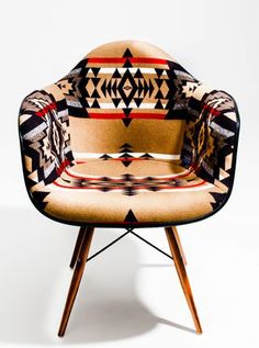 an upholstered chair with native designs on the armrests and back rests against a white background