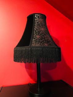 a lamp that is on top of a black stand in front of a red wall