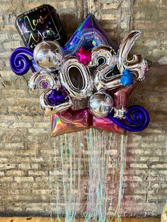 balloons and streamers in the shape of numbers hanging from a brick wall with a happy new year balloon