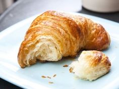 a croissant on a plate with one bite taken out