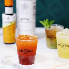 three different types of alcoholic drinks on a marble counter top with bottles in the background