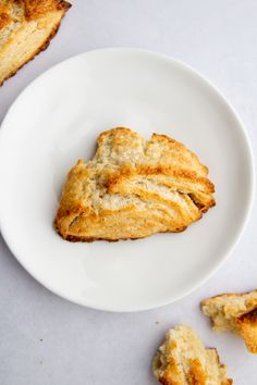 a piece of bread on a plate next to some pieces of biscuits that have been cut in half