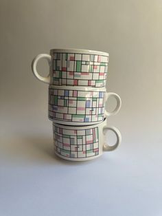 three coffee mugs stacked on top of each other with different colored squares in them