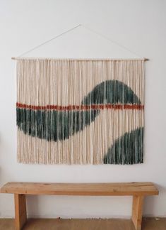 a wooden bench sitting in front of a wall hanging