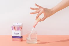 a person is holding a toothbrush in front of a glass of water