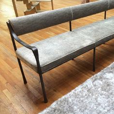 a gray bench sitting on top of a hard wood floor next to a white rug