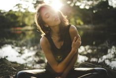 a woman sitting on the ground with her eyes closed and hands folded in front of her face