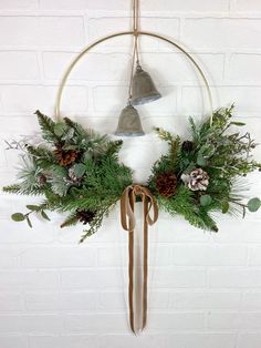 a christmas wreath hanging on the wall with bells and greenery in front of it