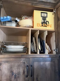 an open cabinet with dishes and other kitchen items in it, including a bunn box